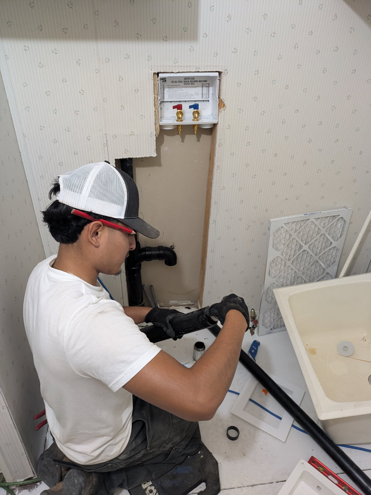 A Reliable Plumbing technician roughing in a laundry box and drain line in a Salt Lake City home