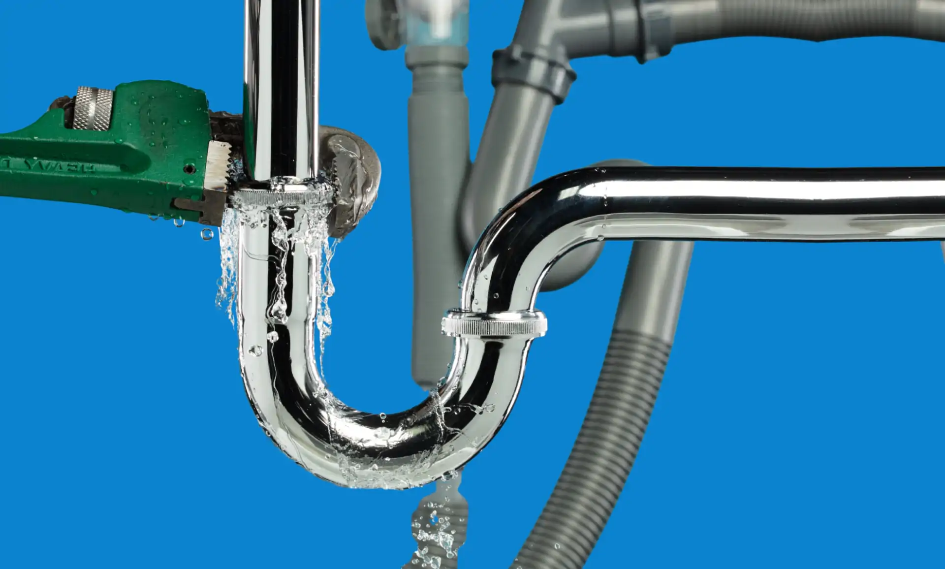 Plumber tightening a leaking chrome sink trap with a pipe wrench, plumbing service for South Jordan, Utah